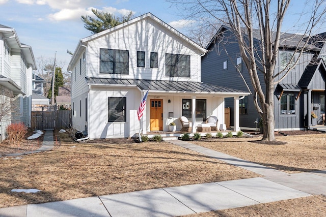 modern inspired farmhouse featuring a standing seam roof, a porch, fence, board and batten siding, and metal roof