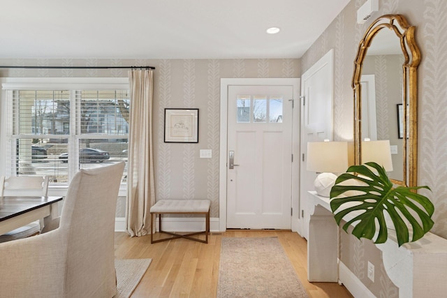 foyer entrance featuring wallpapered walls, light wood-type flooring, and baseboards