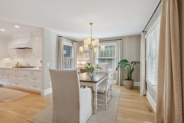 dining area featuring wallpapered walls, baseboards, light wood finished floors, and a chandelier