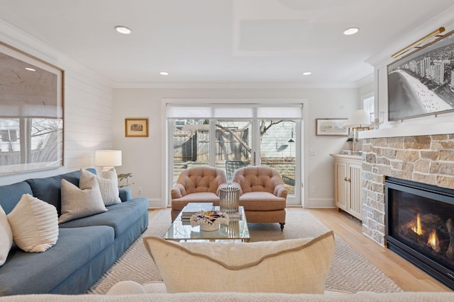 living room featuring a wealth of natural light, a stone fireplace, and light wood finished floors