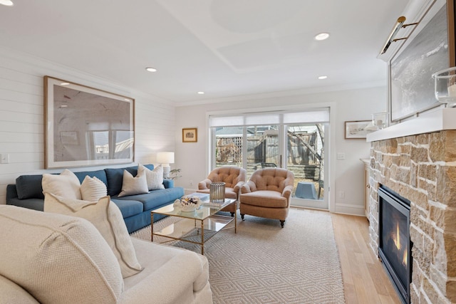 living area featuring wooden walls, crown molding, a fireplace, and light wood finished floors