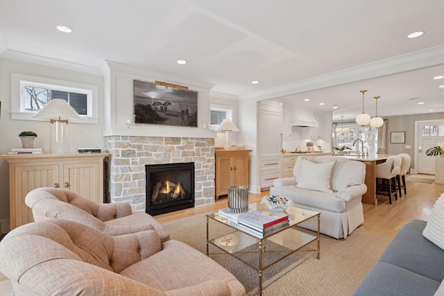 living area with a fireplace, light wood-style floors, a wealth of natural light, and ornamental molding