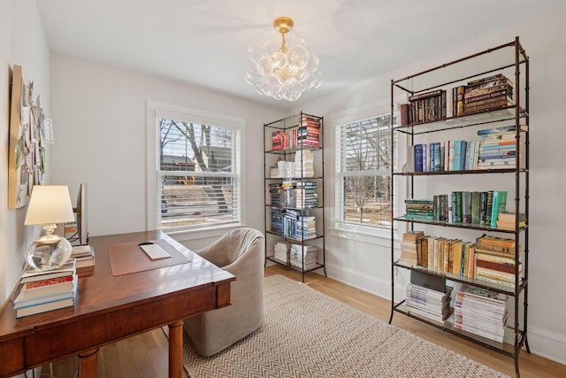 home office with a notable chandelier, wood finished floors, and baseboards