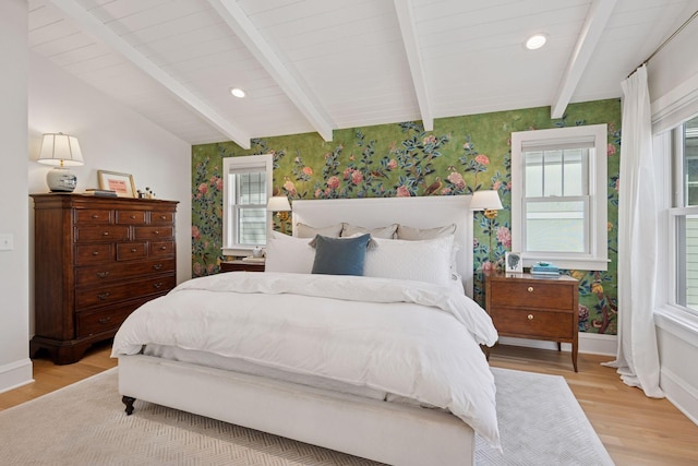 bedroom with lofted ceiling with beams, baseboards, light wood-style floors, and wallpapered walls