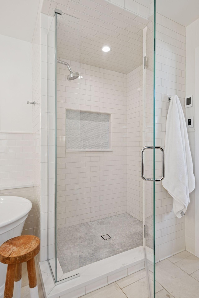 full bathroom featuring a freestanding bath, tile walls, a shower stall, and tile patterned flooring