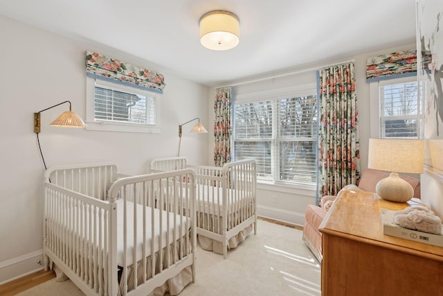 bedroom with a crib, multiple windows, and baseboards