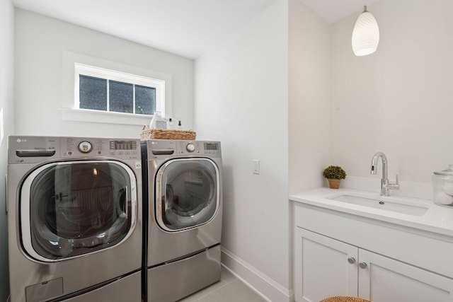 clothes washing area featuring baseboards, cabinet space, a sink, tile patterned flooring, and washer and dryer