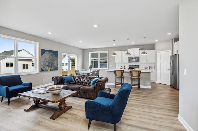 living room with recessed lighting, light wood-style flooring, and baseboards