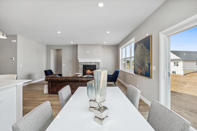 dining space with wood finished floors, recessed lighting, a fireplace, and baseboards