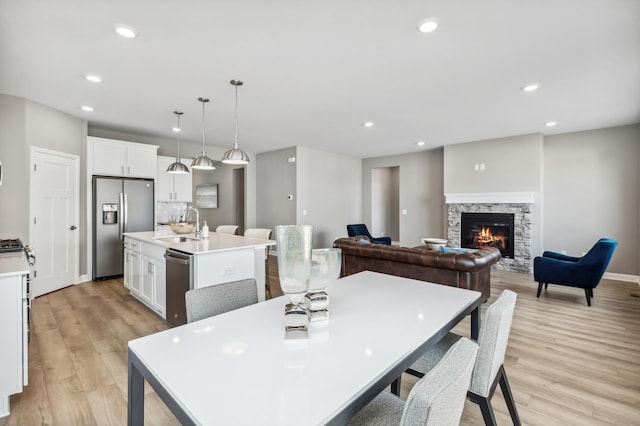 dining area featuring a fireplace, light wood-style flooring, recessed lighting, and baseboards