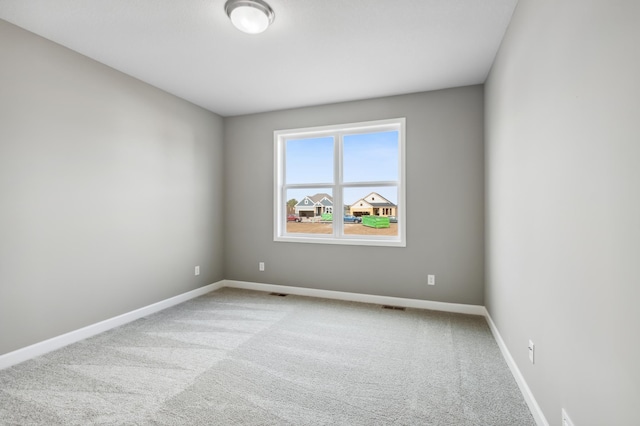 empty room featuring carpet flooring, visible vents, and baseboards