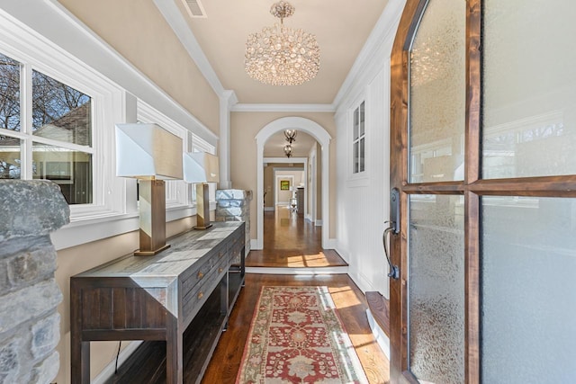 hallway featuring visible vents, an inviting chandelier, arched walkways, ornamental molding, and dark wood-type flooring