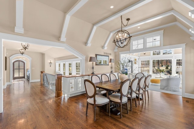 dining area with high vaulted ceiling, baseboards, an inviting chandelier, and wood finished floors