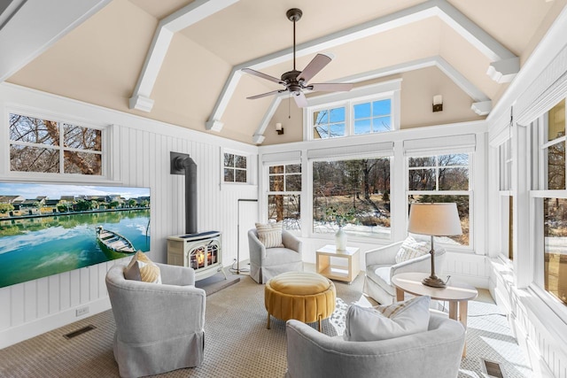 sunroom with lofted ceiling with beams, visible vents, a ceiling fan, and a wood stove