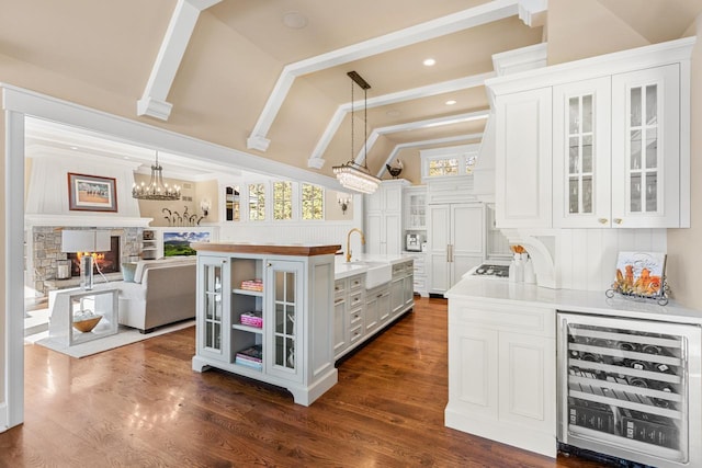 kitchen featuring lofted ceiling, dark wood-style flooring, a sink, wine cooler, and white cabinets