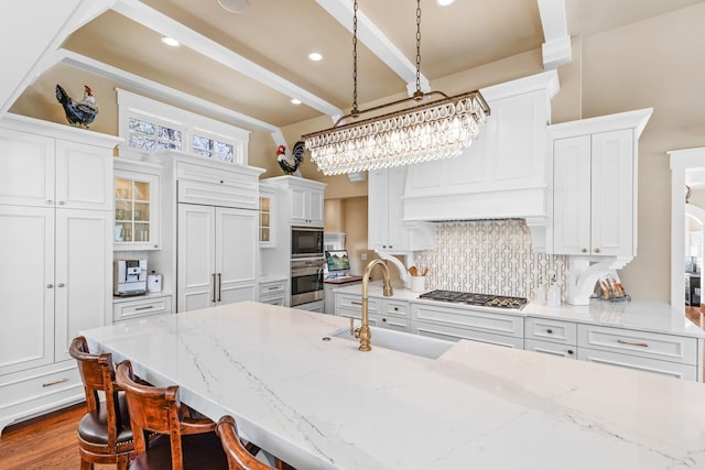 kitchen with a sink, backsplash, white cabinetry, stainless steel appliances, and a breakfast bar area