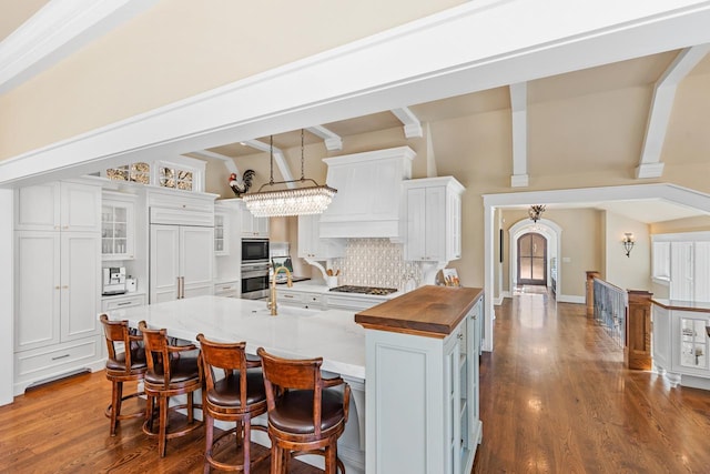 kitchen featuring dark wood-type flooring, white cabinets, built in appliances, wood counters, and backsplash