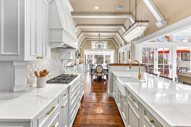 kitchen featuring dark wood-type flooring, a sink, tasteful backsplash, white cabinetry, and stainless steel gas cooktop