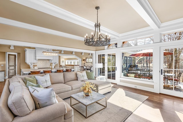 living area featuring beamed ceiling, a notable chandelier, wood finished floors, and ornamental molding