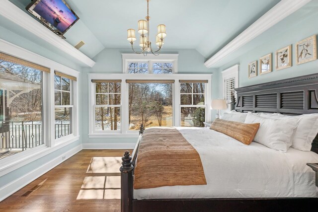 bedroom with visible vents, baseboards, lofted ceiling, an inviting chandelier, and wood finished floors