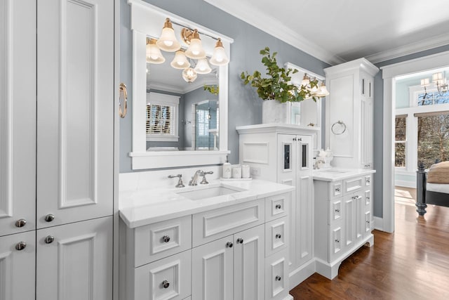 full bath with a notable chandelier, vanity, crown molding, and wood finished floors