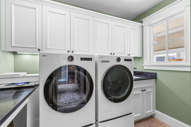 laundry room featuring light tile patterned floors, baseboards, cabinet space, and washing machine and dryer