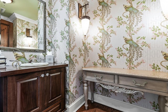 bathroom featuring visible vents, ornamental molding, wallpapered walls, baseboards, and vanity