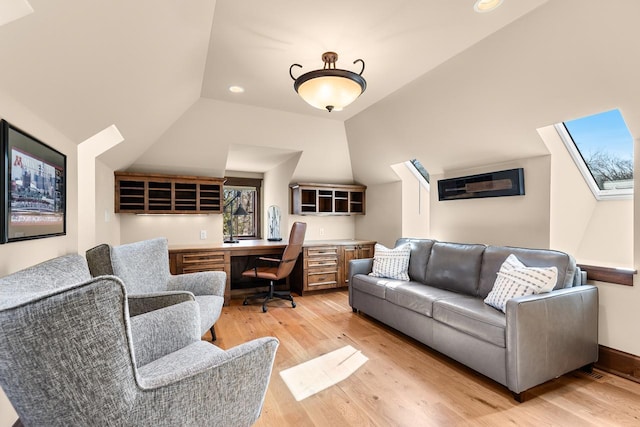 office space featuring light wood finished floors, built in desk, recessed lighting, and vaulted ceiling