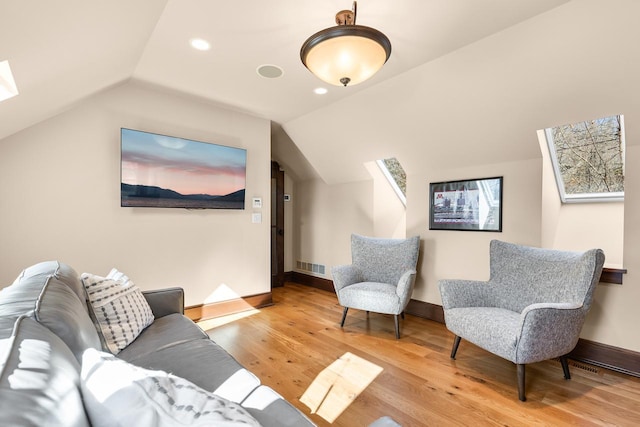 living room with visible vents, baseboards, recessed lighting, vaulted ceiling with skylight, and wood finished floors