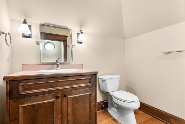 bathroom with vanity, toilet, wood finished floors, and baseboards