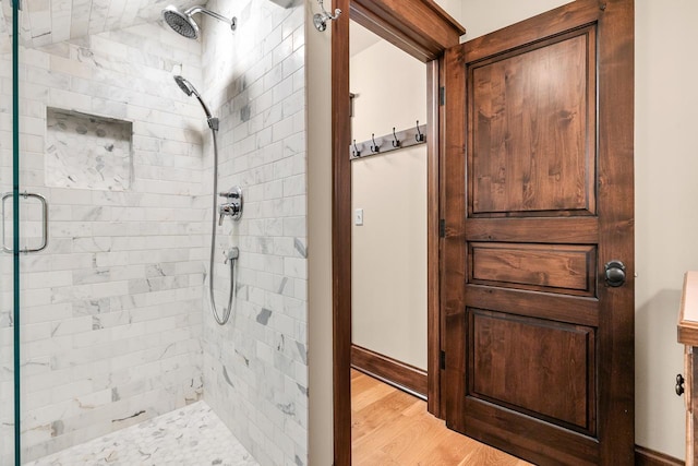 full bathroom with baseboards, wood finished floors, and a stall shower