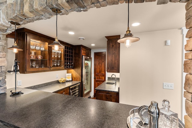 kitchen featuring dark brown cabinets, glass insert cabinets, wine cooler, built in refrigerator, and a sink