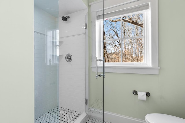 bathroom featuring toilet, a stall shower, and a wealth of natural light