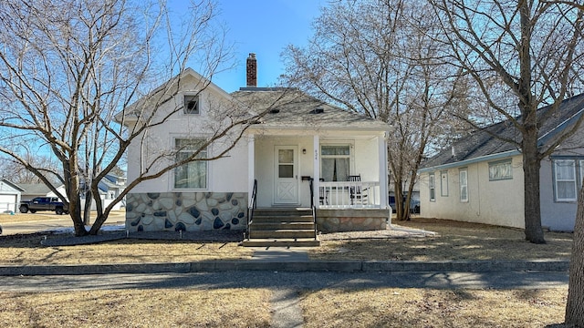 view of front of home featuring a porch, stucco siding, stone siding, and a chimney