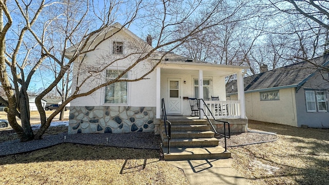 view of front facade with stone siding, stucco siding, and a porch