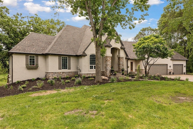 french country inspired facade with a front lawn, stone siding, roof with shingles, and stucco siding