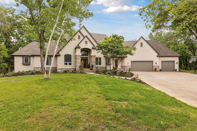 french country home featuring stone siding, an attached garage, driveway, and a front lawn