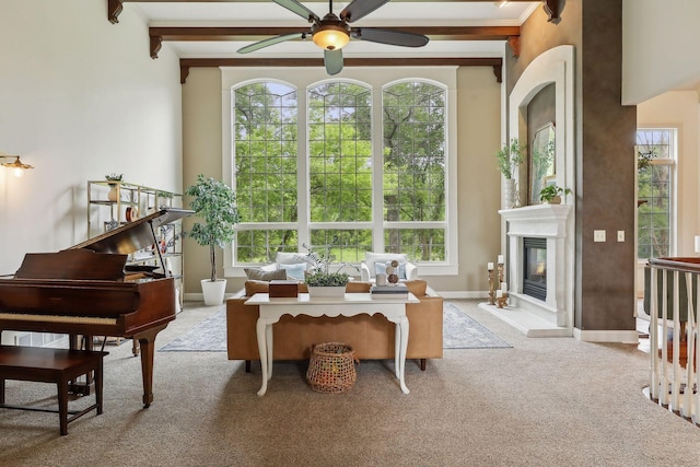 interior space with beam ceiling, a glass covered fireplace, a ceiling fan, and baseboards