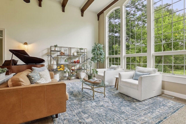 living room with beam ceiling, visible vents, and baseboards