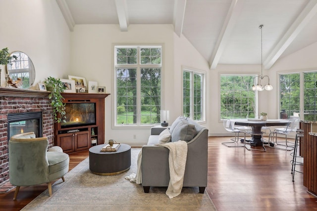 living room featuring lofted ceiling with beams, a notable chandelier, a brick fireplace, and wood finished floors