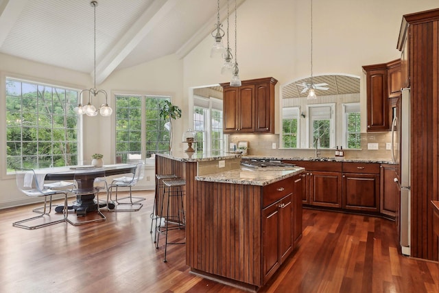 kitchen with dark wood-style floors, backsplash, a breakfast bar area, and light stone counters