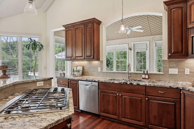 kitchen with light stone counters, vaulted ceiling, stainless steel appliances, and a sink