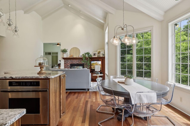 dining room featuring plenty of natural light, a fireplace, lofted ceiling with beams, and wood finished floors