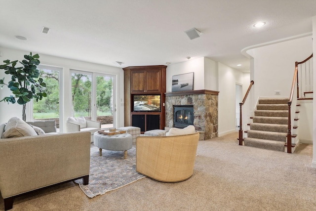 living area with visible vents, recessed lighting, a stone fireplace, light colored carpet, and stairs