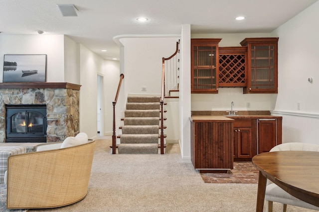 bar with wet bar, stairway, light colored carpet, and a fireplace