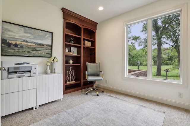 living area with radiator, plenty of natural light, baseboards, and light carpet