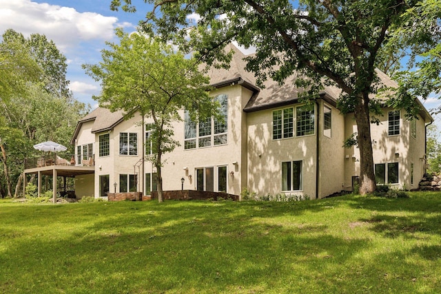 back of property with a lawn, a shingled roof, and stucco siding