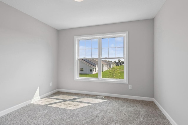 carpeted empty room featuring visible vents and baseboards