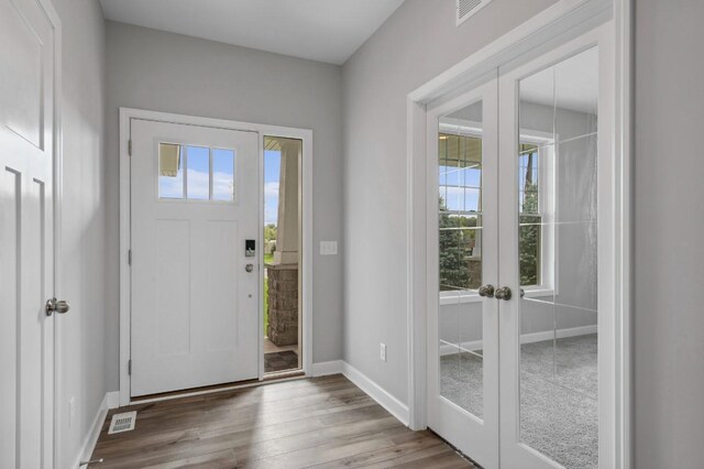 foyer entrance featuring visible vents, wood finished floors, baseboards, and french doors