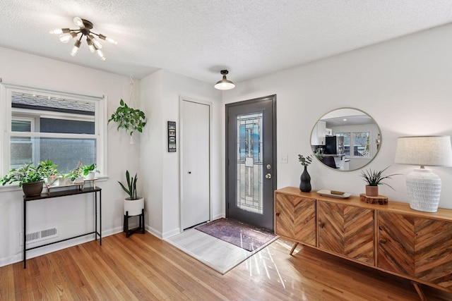 entrance foyer with a wealth of natural light, visible vents, a textured ceiling, and wood finished floors